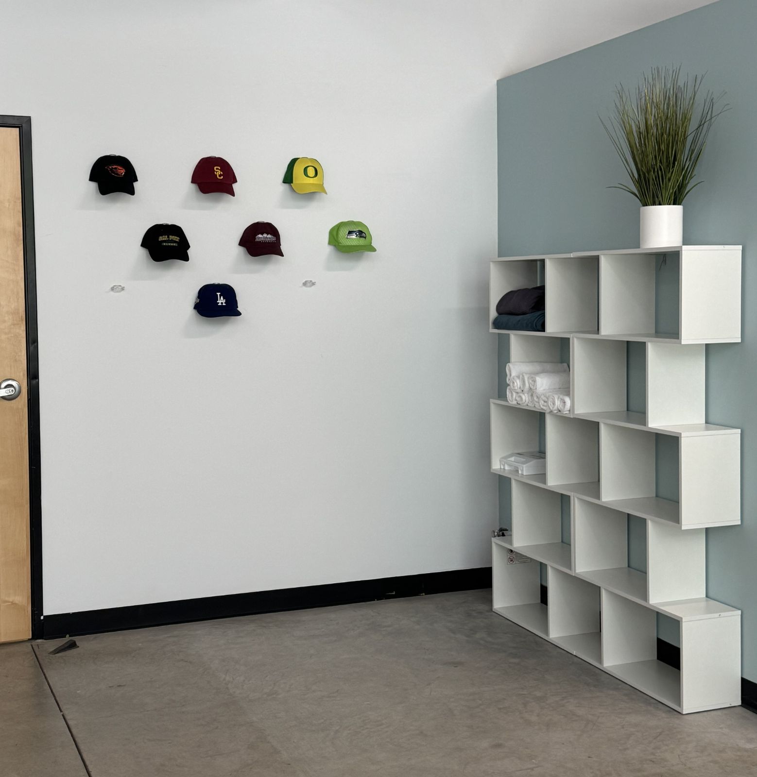 Hat wall celebrating athletes and teams served by Amplify Wellness